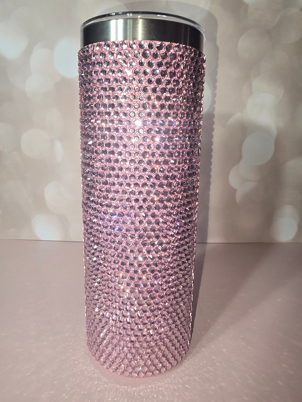 20oz skinny tumbler fully covered in blush pink rhinestones, sparkling against a soft background