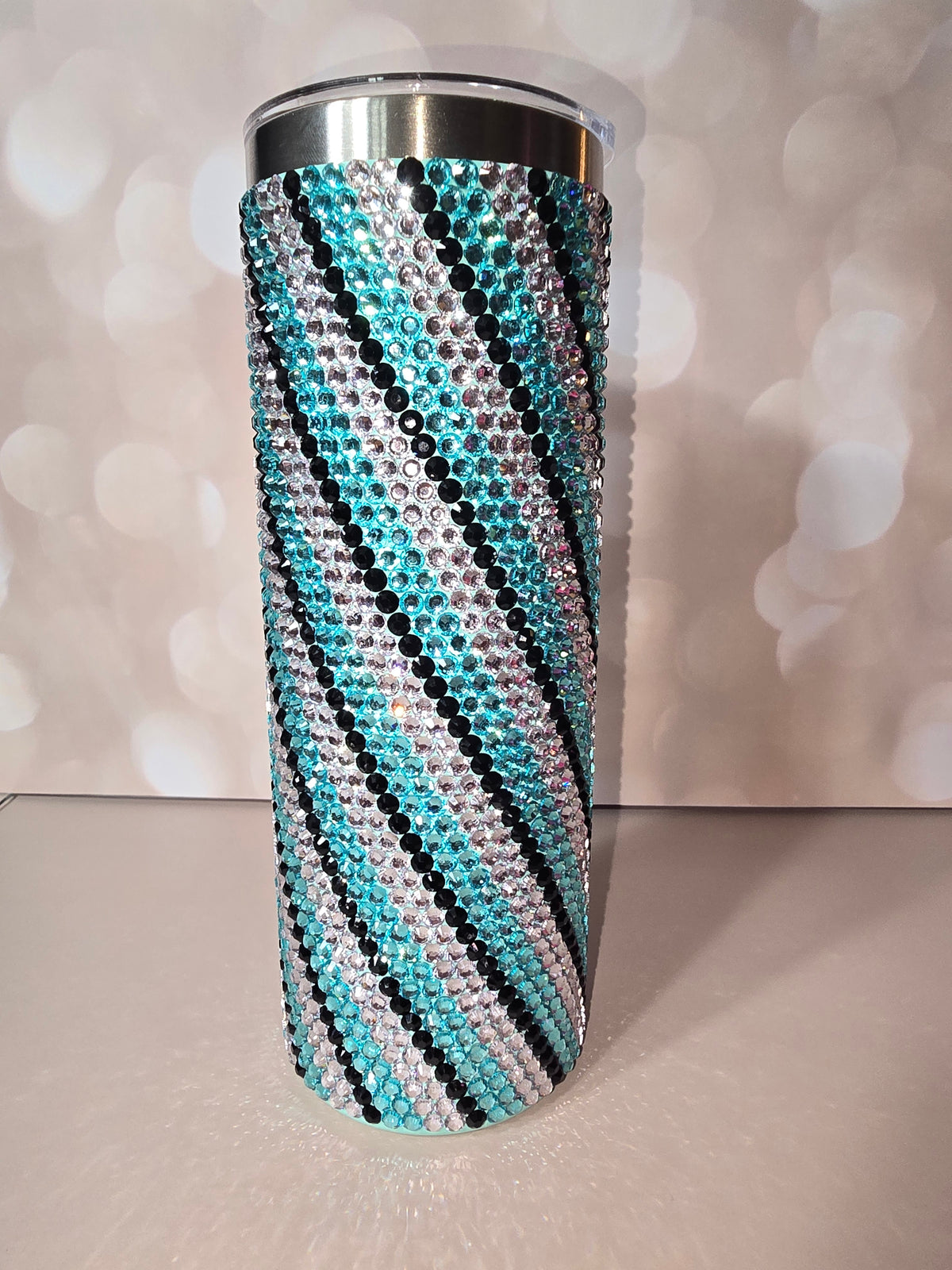 20oz skinny tumbler fully covered in teal, clear, and black rhinestones in a zebra stripe pattern